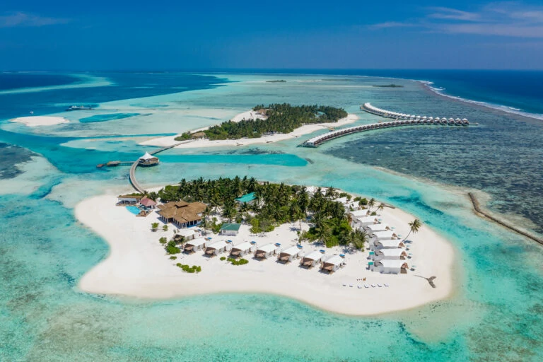Aerial view of Hakuraa surf spot, Maldives with turquoise waters and surfers riding waves – Atoll Travel