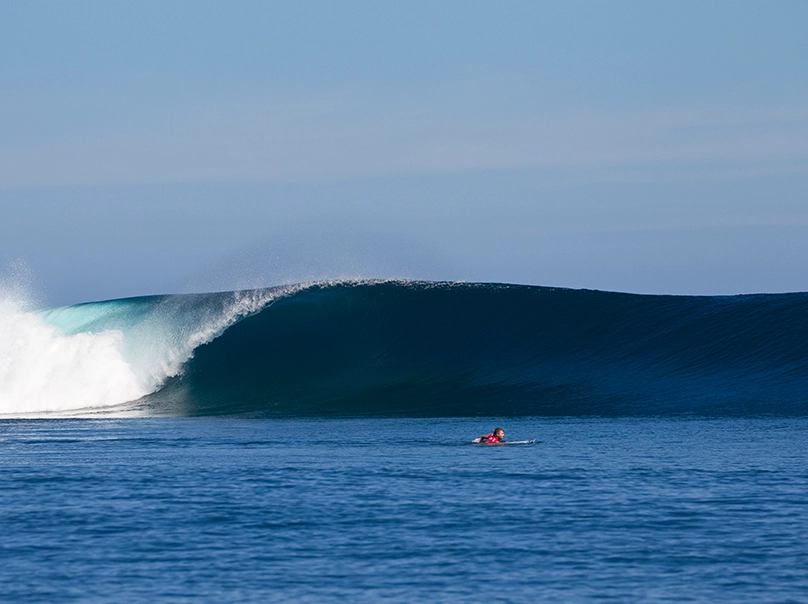 Close-up of a surfer riding a curling tropical wave in Maldives – Atoll Travel