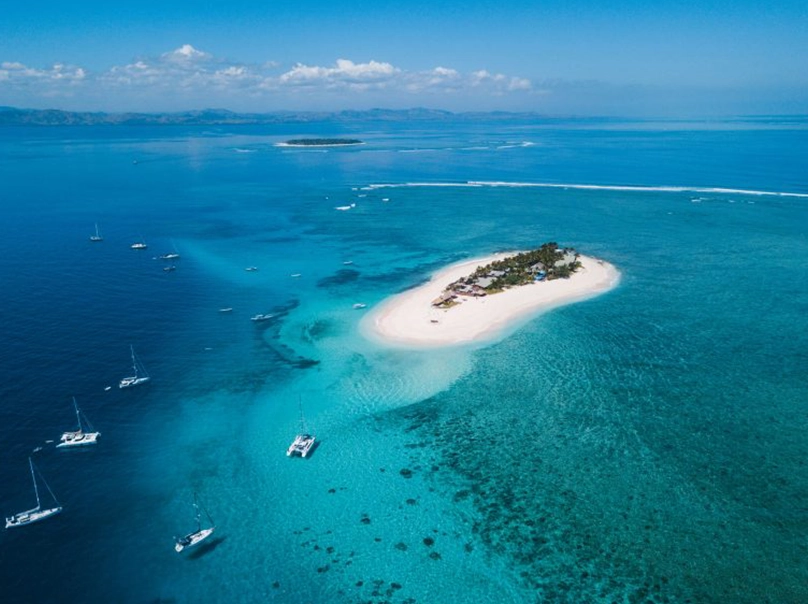 Beach scene with surfers preparing boards and watching waves, tropical surf – Atoll Travel