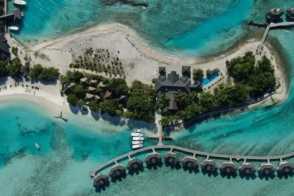 Colorful resort buildings by turquoise ocean, tropical Maldives setting – Atoll Travel