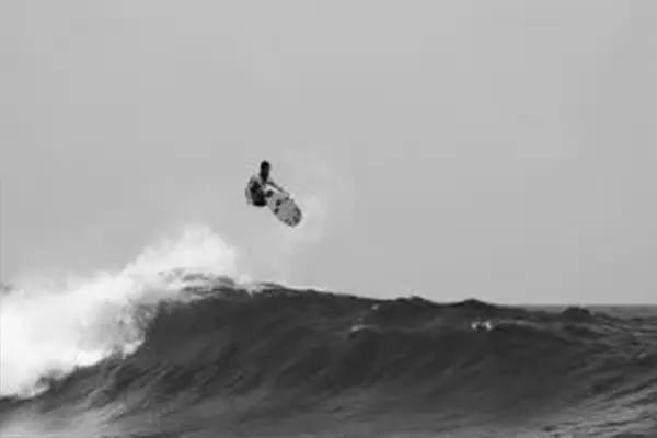 Black and white photo of surfer on wave during action shot, Maldives – Atoll Travel