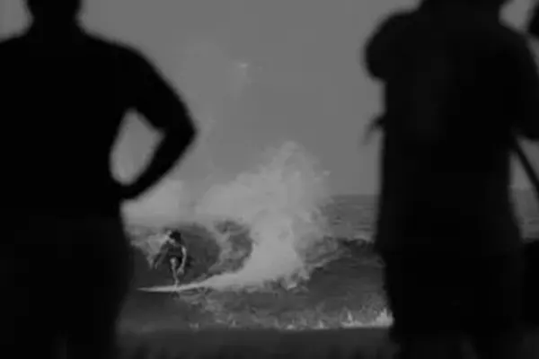 Black and white photo of surfer Miguel riding wave in Maldives – Atoll Travel