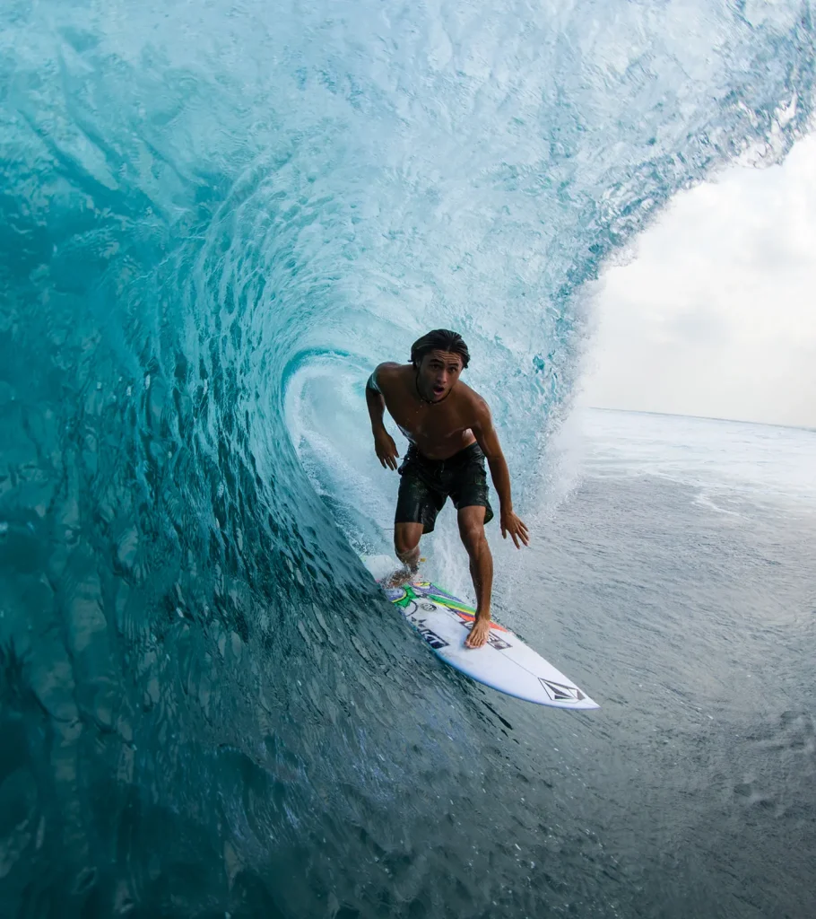 Surfer performing high aerial maneuver above a wave in Maldives – Atoll Travel