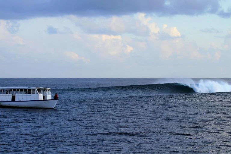 Surfer gliding along turquoise wave with white foam, Maldives – Atoll Travel