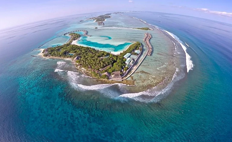 Surfers riding waves in Maldives with clear turquoise waters – Atoll Travel