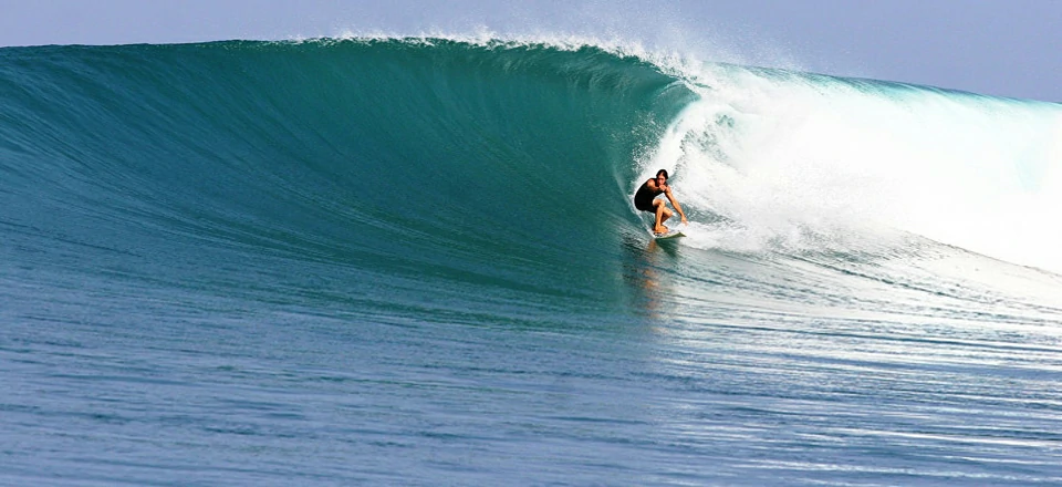 Wide aerial of Nemberala Beach, West Timor showing surfers and reef break – Atoll Travel