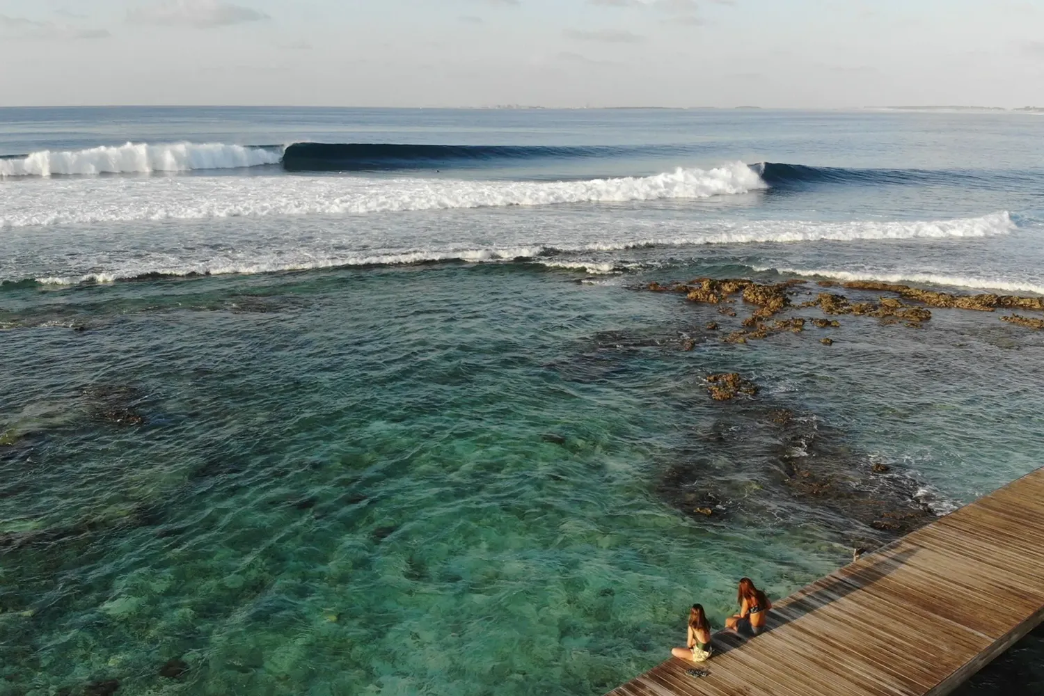 Surfing view at Pasta Point, Maldives with turquoise waves and surfers – Atoll Travel