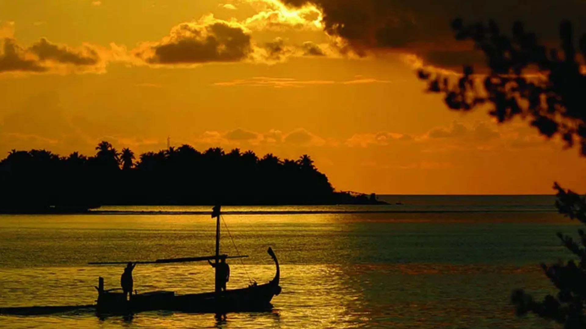 Surfer riding a wave near tropical island coastline in Maldives – Atoll Travel