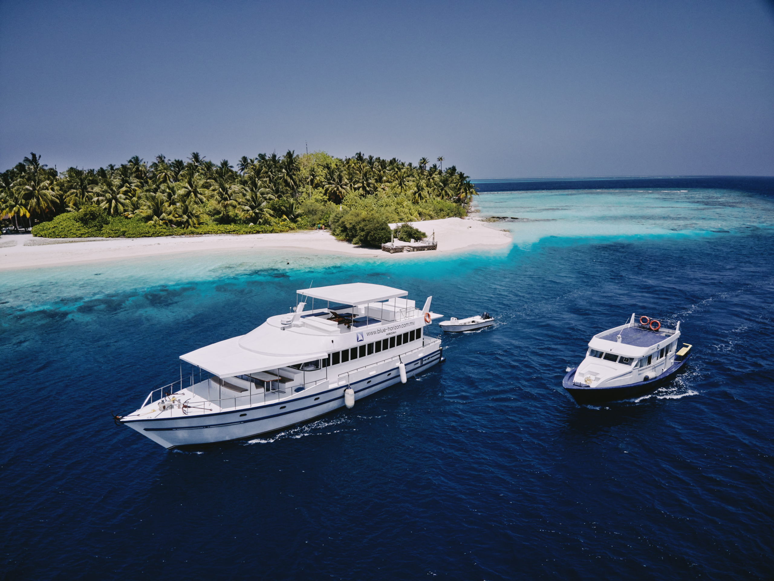 Drone view of surfers paddling out at reef break in Maldives – Atoll Travel