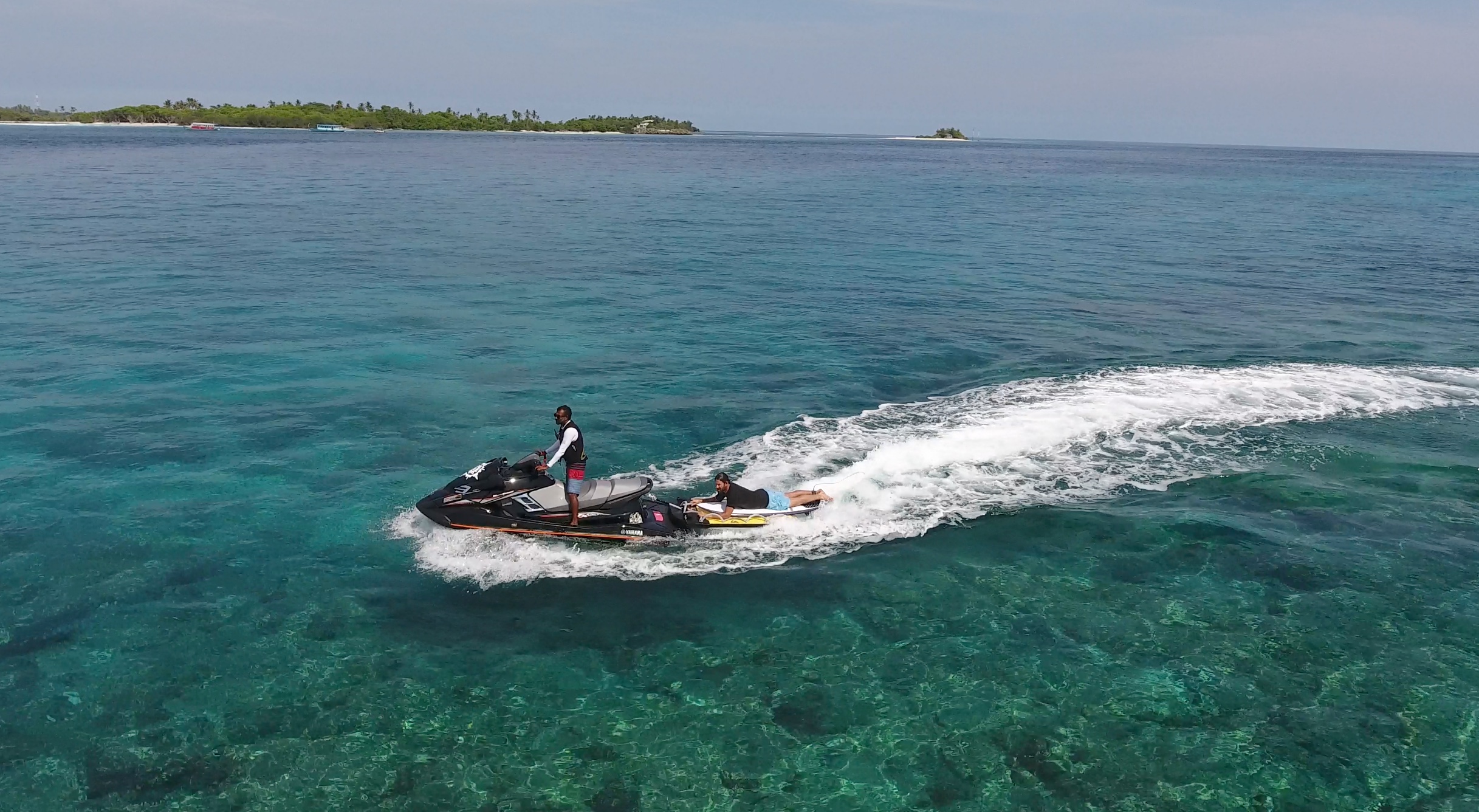 Jet ski speeding across turquoise waters near surf break, Maldives – Atoll Travel